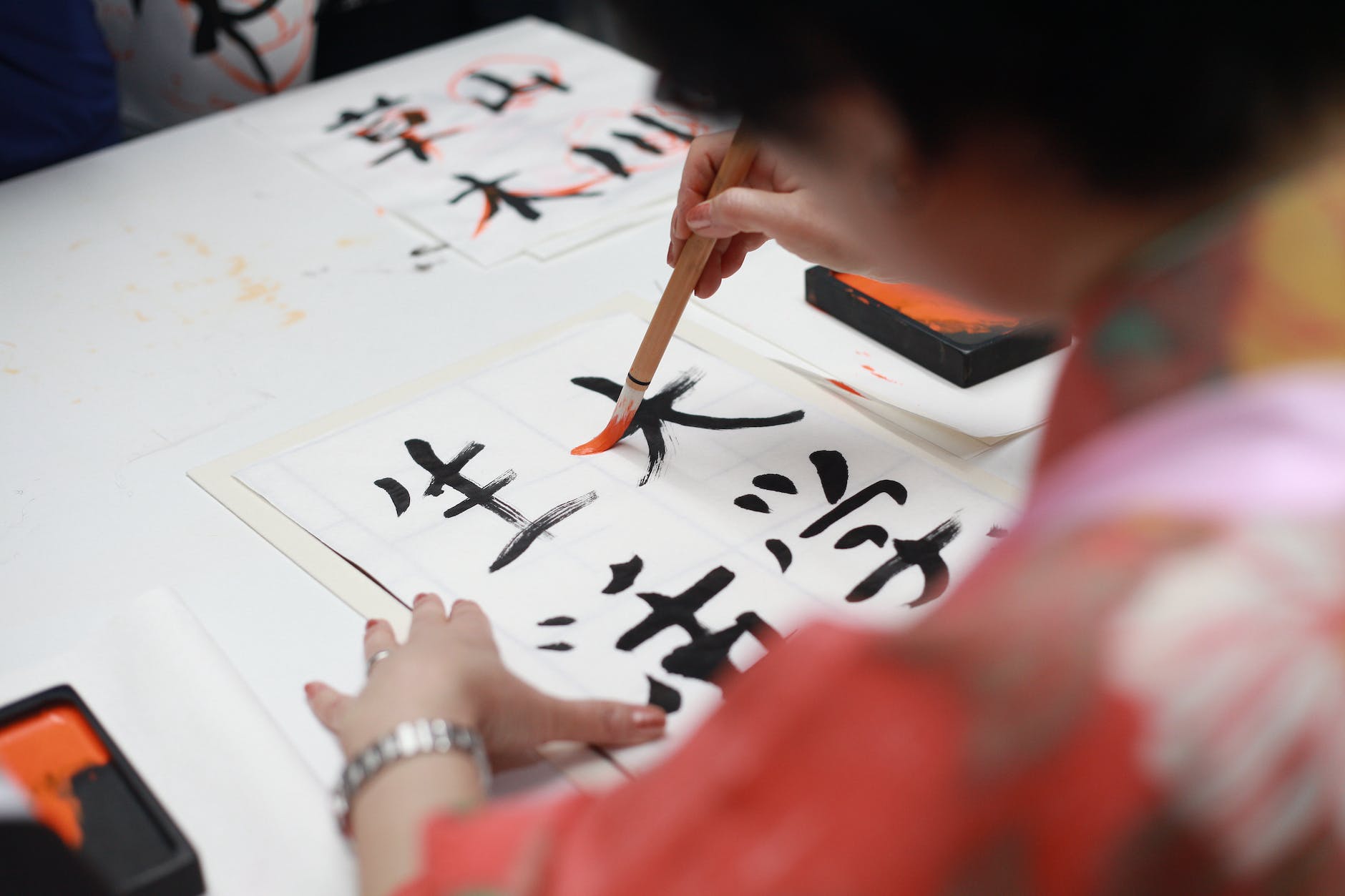 person holding brush drawing kanji script